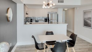 A modern kitchen with a central island, a dining area with four chairs, and a globe on a table.