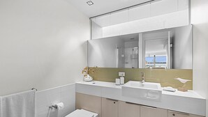 A modern bathroom with a toilet, sink, and mirror. - A Touch Of Class (Lorne)