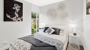 A bedroom with a bed, bedside tables, a wall-mounted artwork, and decorative wall panels. - A Touch Of Class (Lorne)