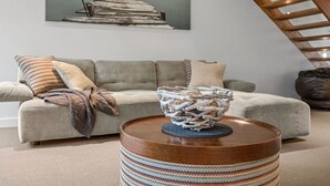 A living room with a sofa, a round wooden coffee table, and a decorative bowl. - A Touch Of Class (Lorne)