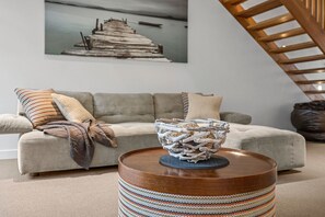 A living room with a sofa, a round wooden coffee table, and a decorative bowl. - A Touch Of Class (Lorne)