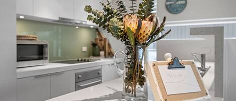 Une cuisine moderne avec un vase en verre transparent contenant des fleurs, posé sur un comptoir blanc.