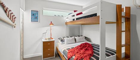 Habitación con literas, un escritorio, una lámpara y un cartel en la pared.