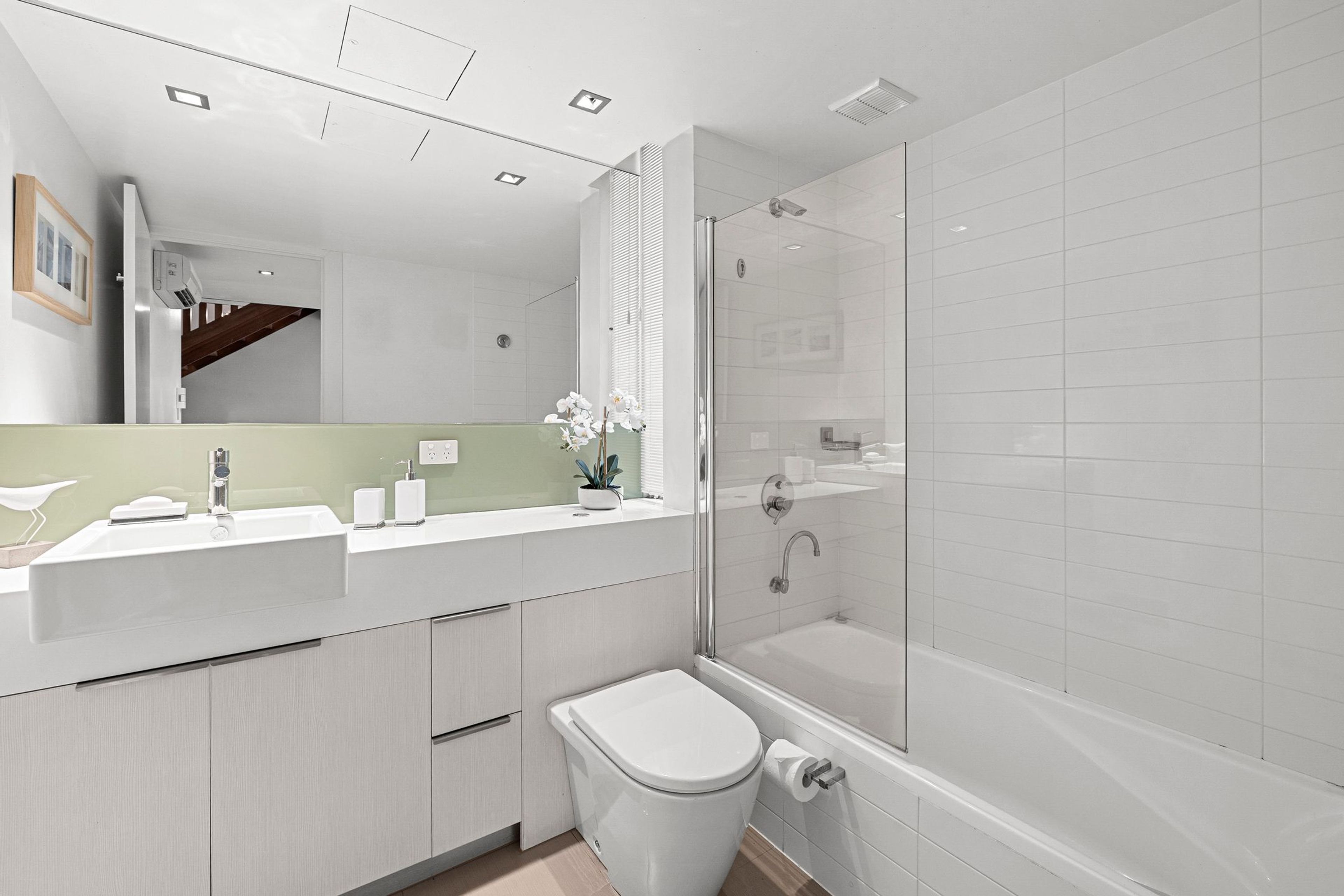 A modern bathroom with a shower, toilet, and sink.