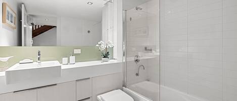 A modern bathroom with a shower, toilet, and sink.