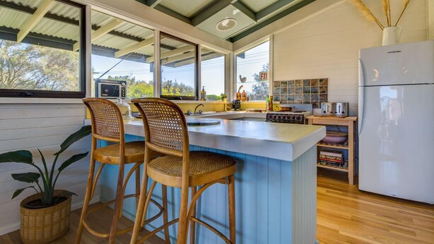 Una cucina moderna con una grande isola, sgabelli da bar, un frigorifero e vista sull'esterno.