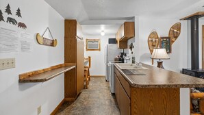 Eine kleine Küche mit Holzschränken, einer Granit-Arbeitsplatte und einem Einbauherd.