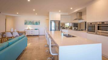A modern kitchen with a central island, stainless steel appliances, and a dining area with a sofa and chairs.
