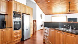 Una cocina con armarios de madera, un refrigerador de acero inoxidable, un horno Bosch y una encimera de granito.