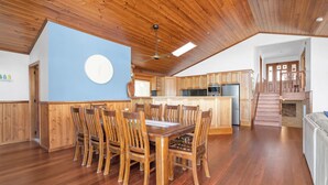 Una cocina amplia con armarios de madera, una isla central y una zona de comedor con sillas de madera.