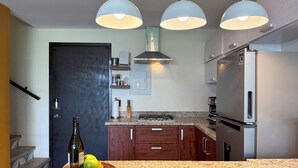 Cozinha moderna com bancadas de granito, eletrodomésticos de aço inoxidável e iluminação pendente.