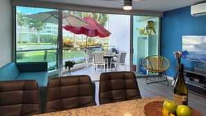Uma sala de estar moderna com área de jantar, janelas amplas e ventilador de teto.