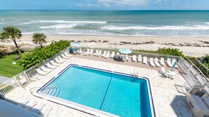 A pool area with lounge chairs and umbrellas, overlooking a beach and ocean. - Oceanfront 2BR Condo 3rd Floor Balcony Views, Unit 307 (Indian Harbour Beach)