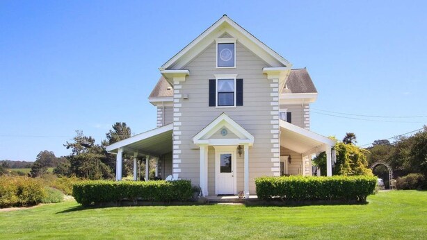 A two-story house with a front porch, a central entrance, and a small front yard.