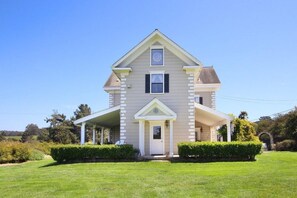 A two-story house with a front porch, a central entrance, and a small front yard.