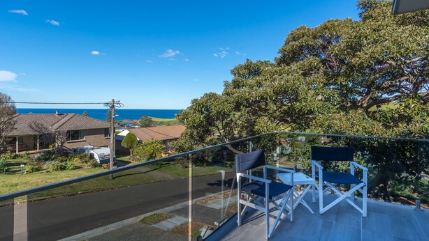 A balcony with outdoor furniture, a clear view of the ocean, and residential buildings in the background. - Coastline, Boat Harbour - Gerringong (Gerringong)