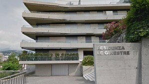 Un edificio residencial de varios pisos con un diseño arquitectónico moderno, que cuenta con balcones y una entrada porticada.