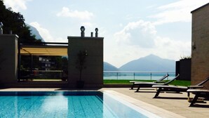 Una piscina con sillones de descanso y vistas a montañas.