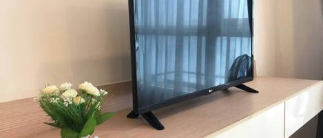 A flat-screen TV on a wooden desk with a white cabinet underneath.