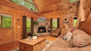 Ein gemütliches Blockhaus-Interieur mit Kamin, Holzmöbeln und einem Fernseher.