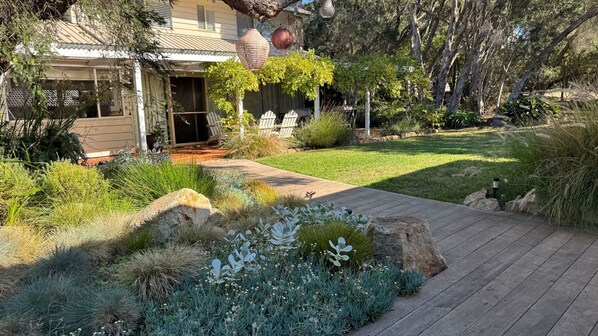 A residential property with a paved driveway, a lawn, and a variety of plants and shrubs.