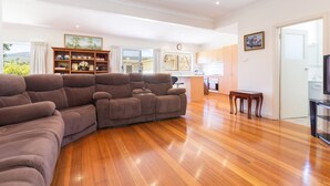 Un salón amplio con un sofá seccional grande, suelo de madera, una zona de cocina y una mesa de comedor.