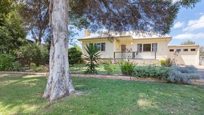 Una casa de un piso con patio delantero, garaje y un árbol grande.