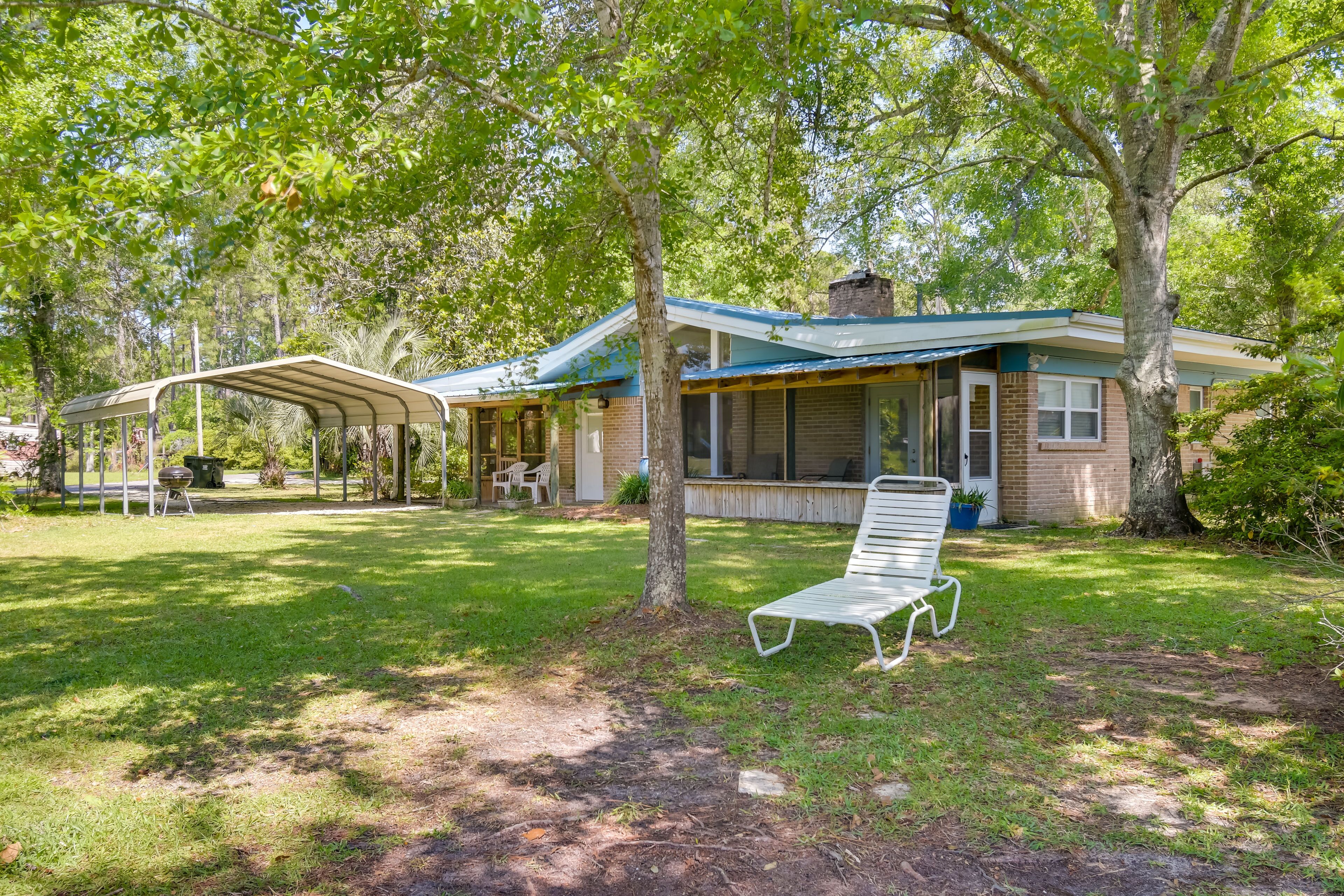 A house with a covered porch, a lawn, and a bench.