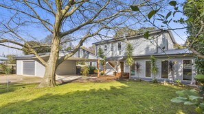 Stunning two-story home with a covered porch and gabled roof, featuring a detached garage and beautifully manicured lawn.