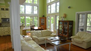 Uma sala de estar ampla com uma janela grande, área de jantar e cozinha com armários de madeira.
