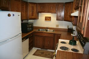 Functional kitchen with a stove, sink, refrigerator, and microwave.