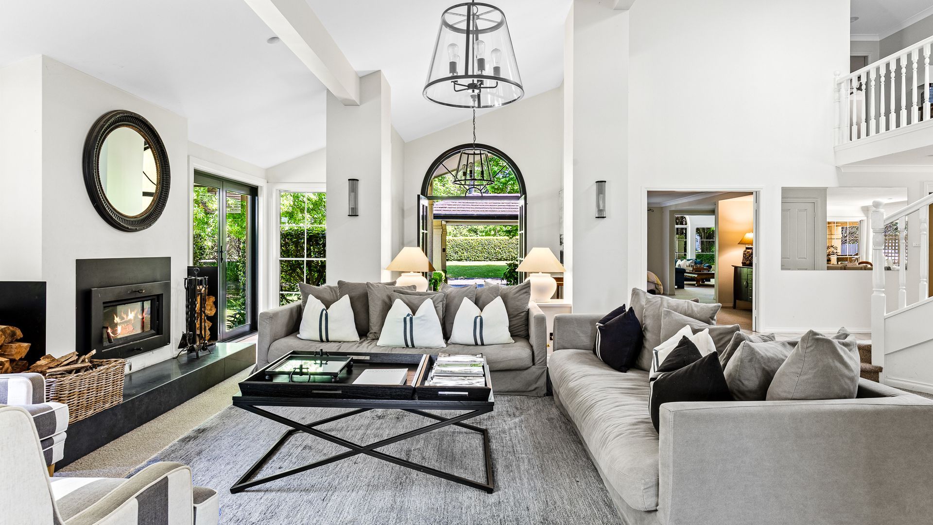 A spacious living room with a fireplace, a large mirror, and a view of the outdoors.
