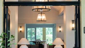 Une pièce spacieuse avec une grande fenêtre, un lustre et une table entourée de chaises.