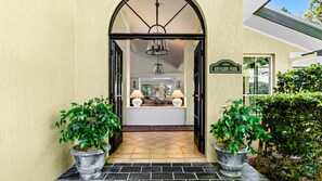 A doorway leading to a living room with a sofa, two lamps, and a chandelier.