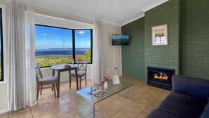 A living room with a large window, a fireplace, a television, and a sofa.