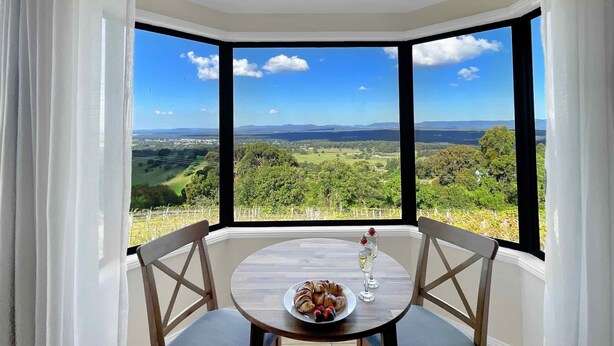 A corner room with a large window offering a scenic view of a valley and distant mountains.