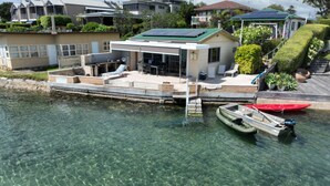 A waterfront property with a dock, a small boat, and a house with a green roof.