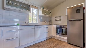A modern kitchen with white cabinetry, a stainless steel refrigerator, an oven, and a dishwasher.