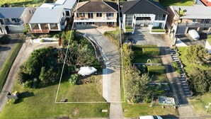 A residential area with multiple houses, a paved driveway, and a well-maintained lawn. - Sunset on Headland, Gerroa (Gerroa)