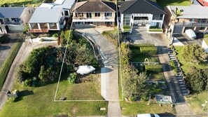 A residential area with multiple houses, a paved driveway, and a well-maintained lawn. - Sunset on Headland, Gerroa (Gerroa)