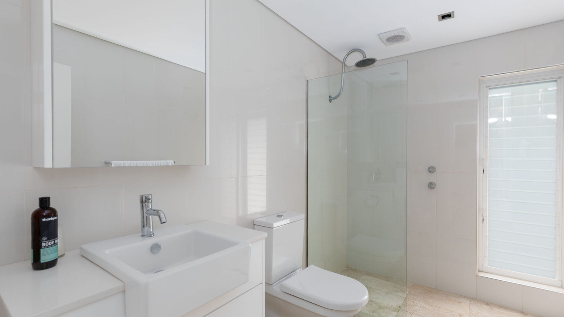 A modern bathroom with a glass-enclosed shower, a white sink, and a toilet.
