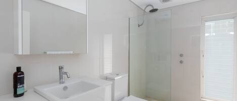 A modern bathroom with a glass-enclosed shower, a white sink, and a toilet.