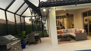 Zona exterior coberta amb piscina, una barbacoa i zona d'estar amb sofà i cadires.
