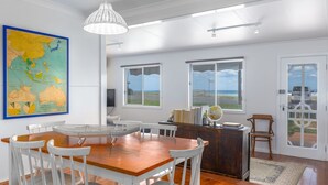 A dining area with a wooden table and white chairs, a globe, and a map on the wall. - Seaways, Gerroa, South Coast (Gerroa)