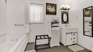 A modern bathroom with a bathtub, white vanity, and a large mirror.