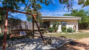 A rustic house with a porch, a swing set, and a gravel pathway.