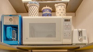 A compact kitchenette with a microwave, a small refrigerator, and a water dispenser.