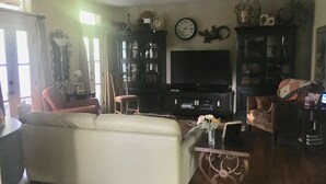 Uma sala de estar com um sofá, uma televisão e uma estante de livros.