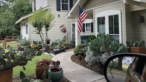 Uma casa de dois andares com varanda frontal, um jardim de cactos e uma bandeira americana.