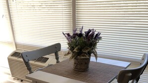 A dining area with a table and chairs, a potted plant, and a window with blinds. - Capital City Condo #1 close to Interstate, Water Park, Restaurants and Shopping (Frankfort)